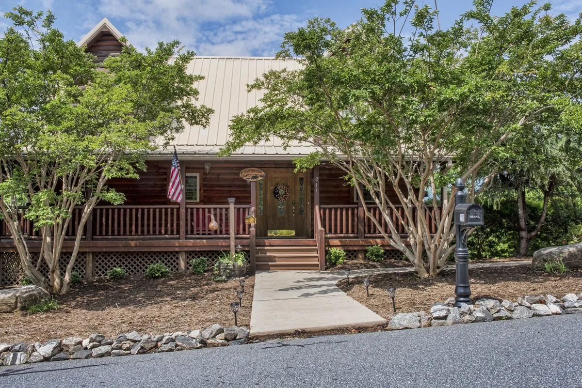 An exterior view of the front porch with a door and flag, styled for comfort and relaxation. The porch is designed for social gatherings, with a welcoming atmosphere that encourages enjoying sunsets or simply being together outdoors.