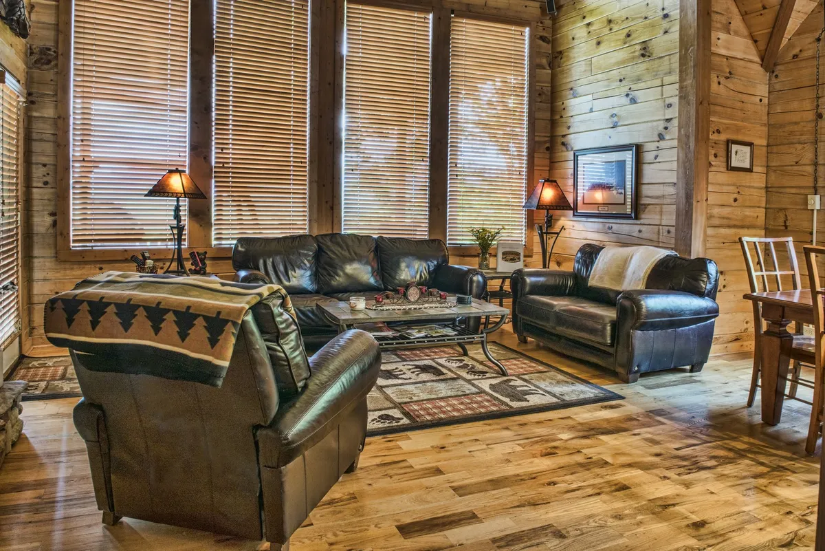 A spacious interior living area with leather sofas, a coffee table, a wooden dining table, and large windows letting in natural light. The setting is conducive to group activities such as board games, shared meals, and cozy conversations, perfectly embodying communal togetherness.